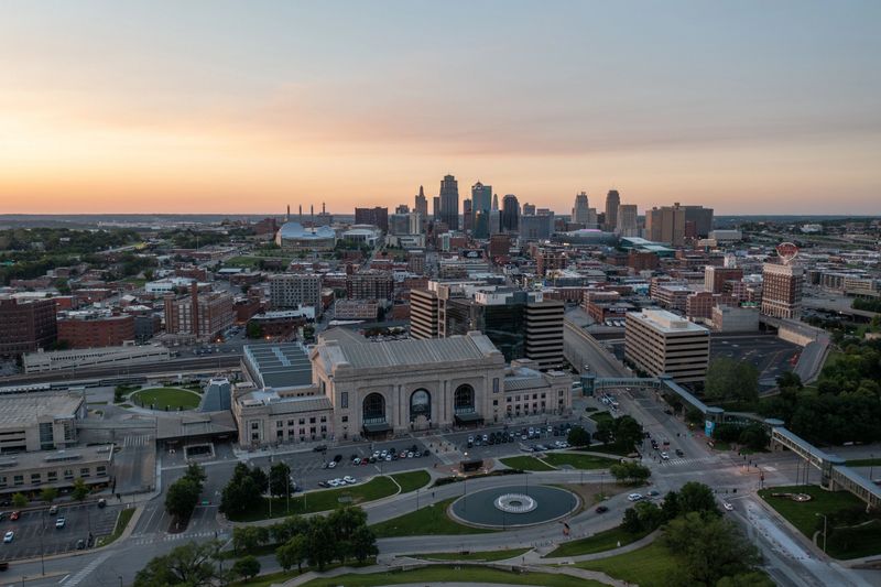 Wide drone shot of the Kansas City skyline featuring Union Station in the foreground, with modern buildings and urban sprawl under vibrant skies.