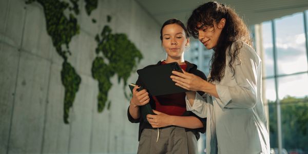 Teacher guiding students using a tablet in a classroom.