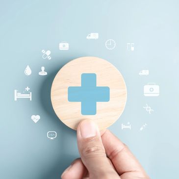 Hand holding a wooden medical cross symbol with healthcare icons around.