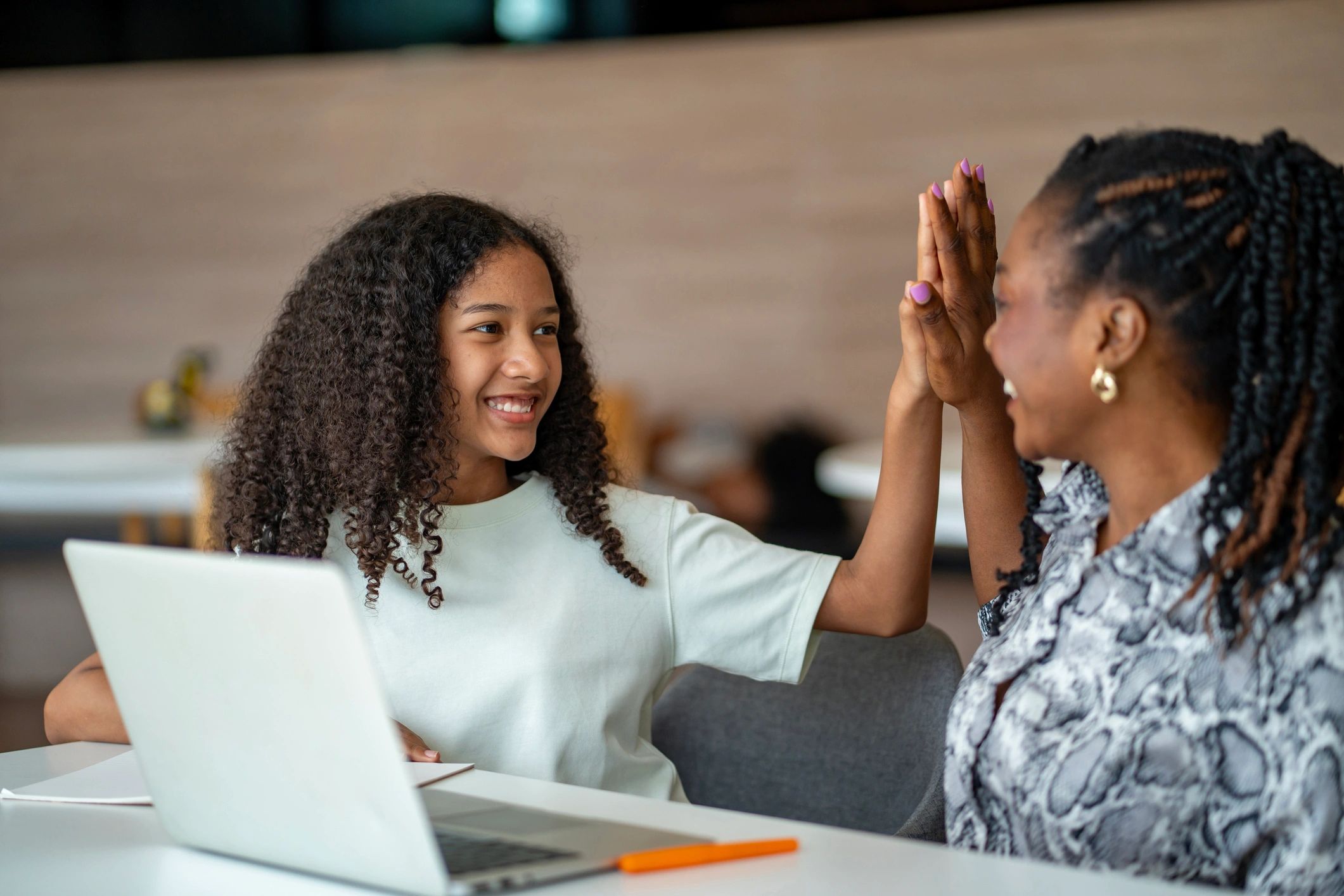 Smiling girl and woman giving a high-five indoors.