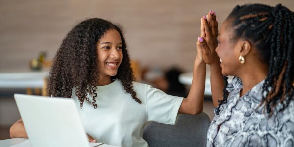 Girl and woman giving a high five, smiling.