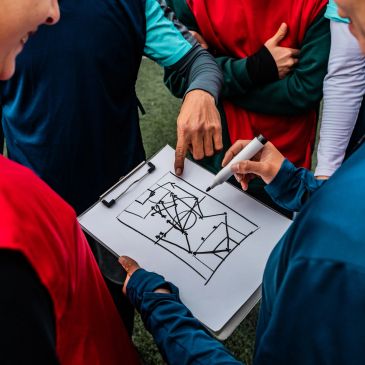 Team planning strategy with a clipboard showing a sports play.