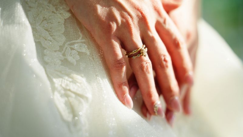 A close-up video of a young bride hand lit by sunlight, and also her wedding ring is visible in the scene.