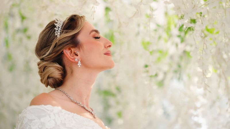 A portrait of a young bride in a white wedding dress. She's standing and facing up with her eyes closed.