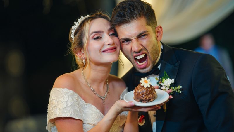A newlywed bride and groom is posing for a photo session with their wedding cake at their wedding ceremony.