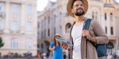 Smiling traveler with map and backpack in a city.