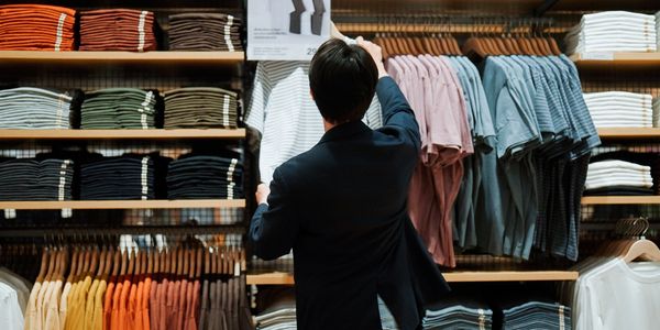 Person browsing neatly arranged folded and hanging shirts in a store.