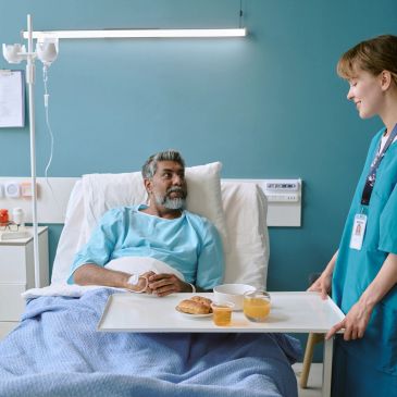 Nurse serving food to a hospital patient.