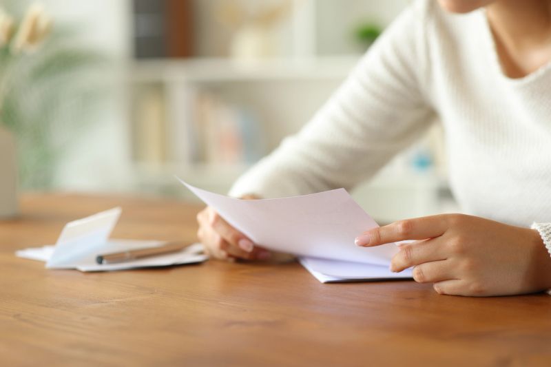 Close up of a woman hands holding and reading a book at home.