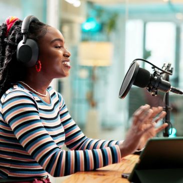 Jeune femme souriante en train d'enregistrer un podcast avec un micro et un casque.