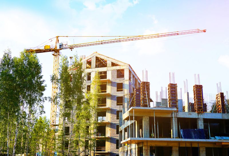 Tower crane on apartment construction. Block House building construction. Apartments construction. Housing renovation, real estate. Crane on formwork in green environment. Modern building renovation.