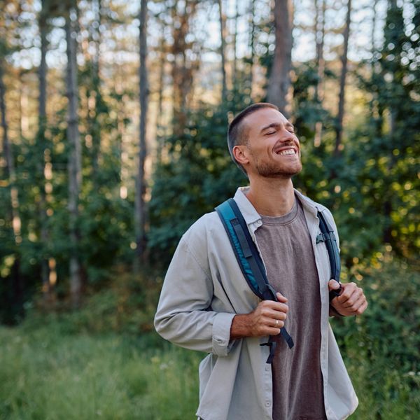 A man enjoying a peaceful walk in the forest with a backpack.