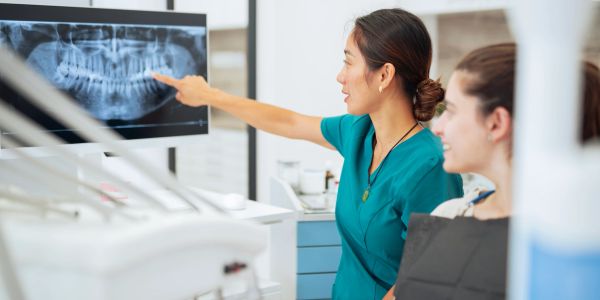 Dentist explaining a dental X-ray to a patient in a clinic.