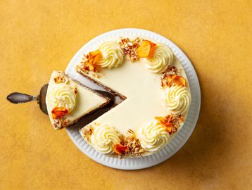 A slice of cream-topped chocolate cake is removed.