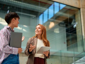 Two women discussing work in a modern office building.