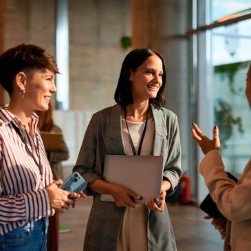 Three women engaged in a friendly conversation indoors.