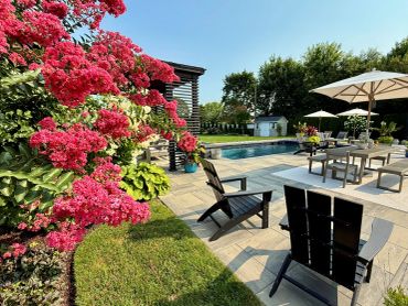 Poolside backyard with pink flowers and seating area