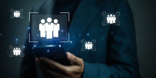 Person holding smartphone with glowing icons of business people around.