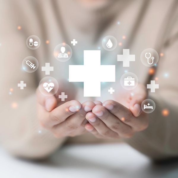 Hands holding glowing medical symbols including a cross and healthcare icons.