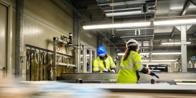 Workers in safety gear operating machinery in a factory.