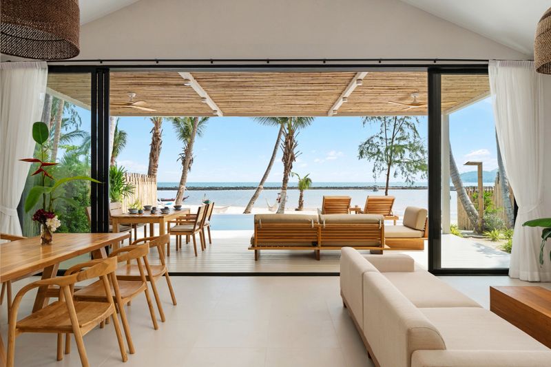 Modern living room and dining area with elegant furniture and a private balcony overlooking the ocean.
