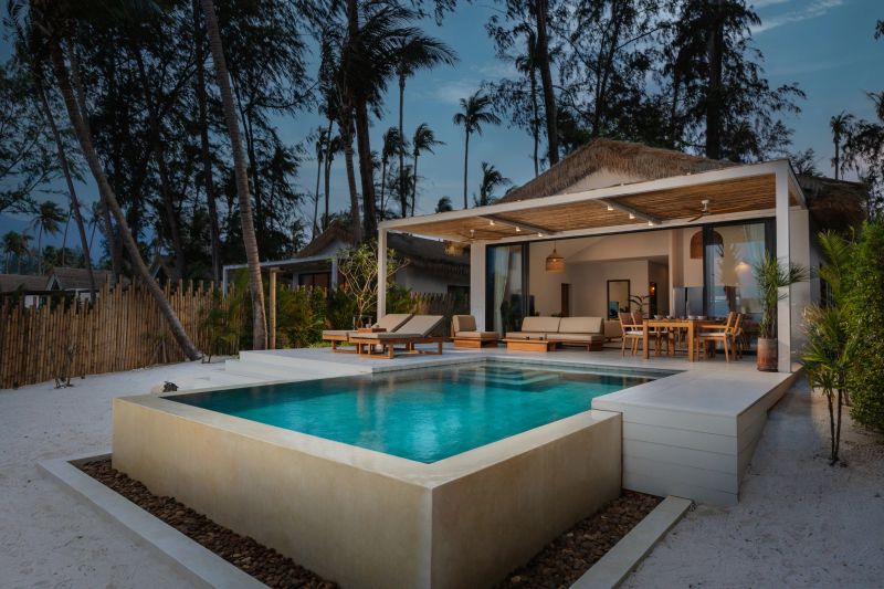 Twilight shot of a luxury beachfront villa with an infinity pool, showcasing elegant architecture.