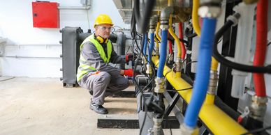 Engineer inspecting colorful industrial pipes and machinery in a facility.