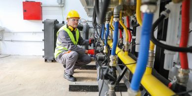 Technician inspects pipes in an industrial setting.