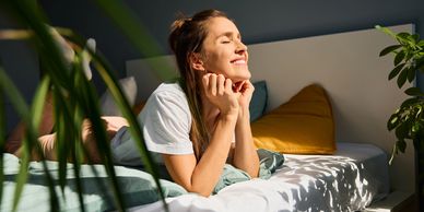 Woman relaxing on bed in sunlight.