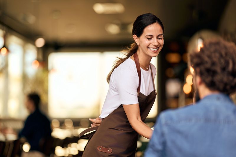 Waitress cheerfully interacting with a customer in a warm and inviting dining location.