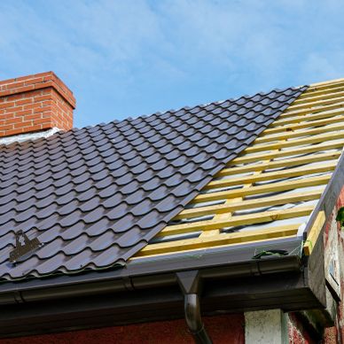 Roof with half-installed dark tiles and chimney.
