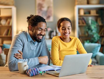 Two people happily working on a laptop at a table.