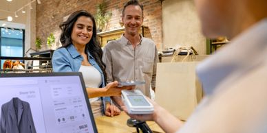 A couple making a contactless payment at a store counter.