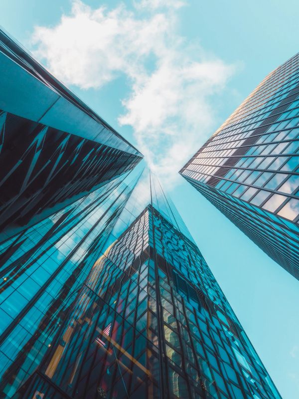 Upward view of modern glass skyscrapers against a blue sky.