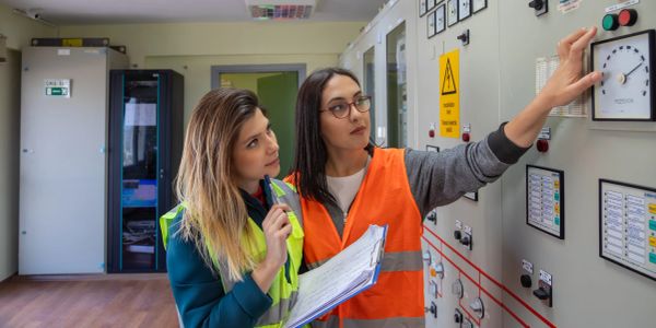Two women examining control panel gauges.