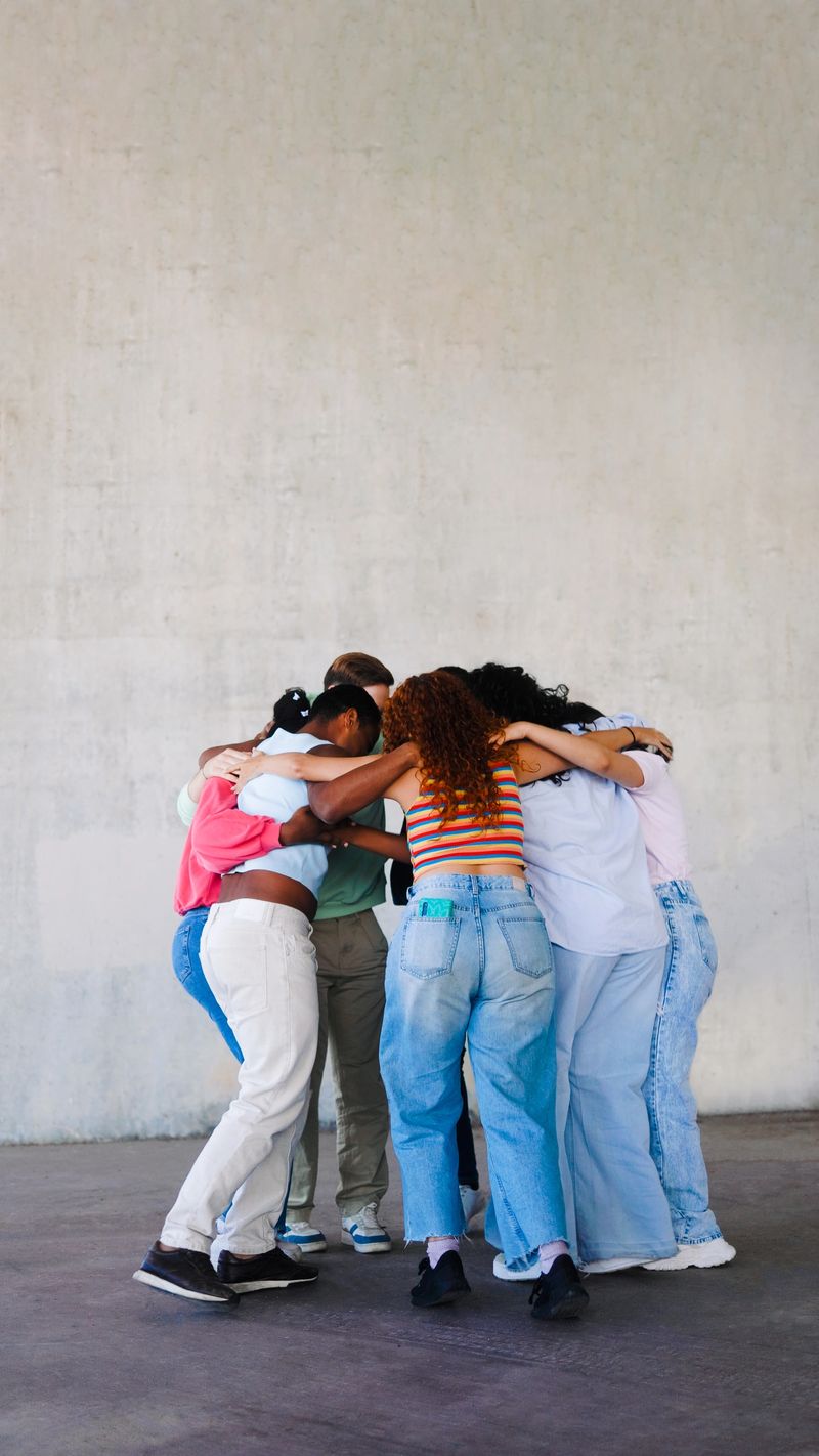 Multiracial group of people hug in circle outdoor. Youth community, support, unity, help concept