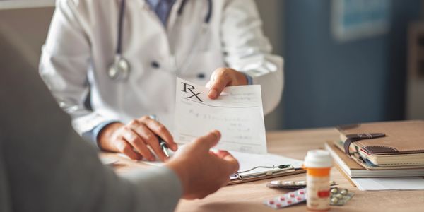 Doctor handing a prescription to a patient in a clinical setting.