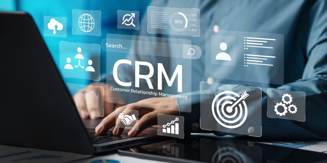 Person using CRM software on a laptop with digital icons.