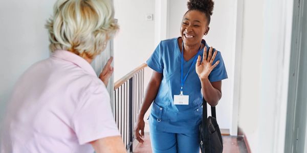 Smiling nurse greeting a woman at home.