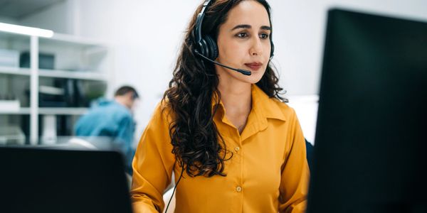 Woman in yellow shirt working with headset in an office.