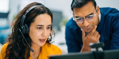 Two colleagues focused on a computer screen, collaborating in an office setting.