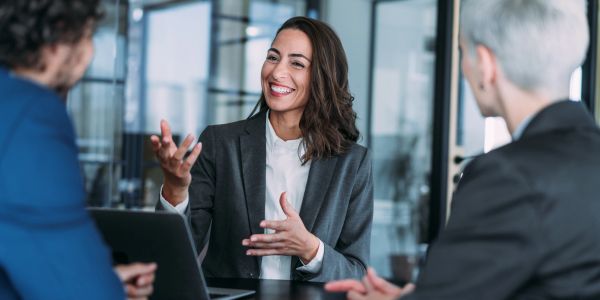 Businesswoman smiling and discussing with colleagues in an office.
