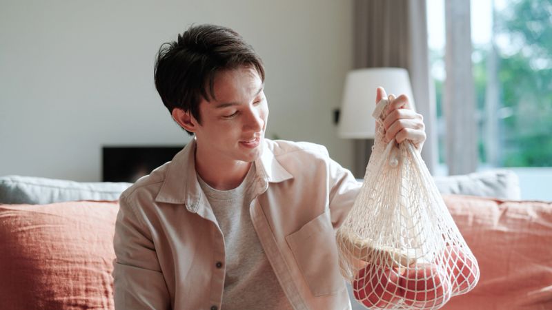 Asian man preparing fruit in reusable bag , zero waste
