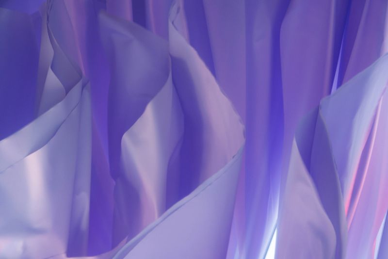 Silk-like textures ripple gently in soothing lavender tones, illuminated by soft, diffused light at dusk.