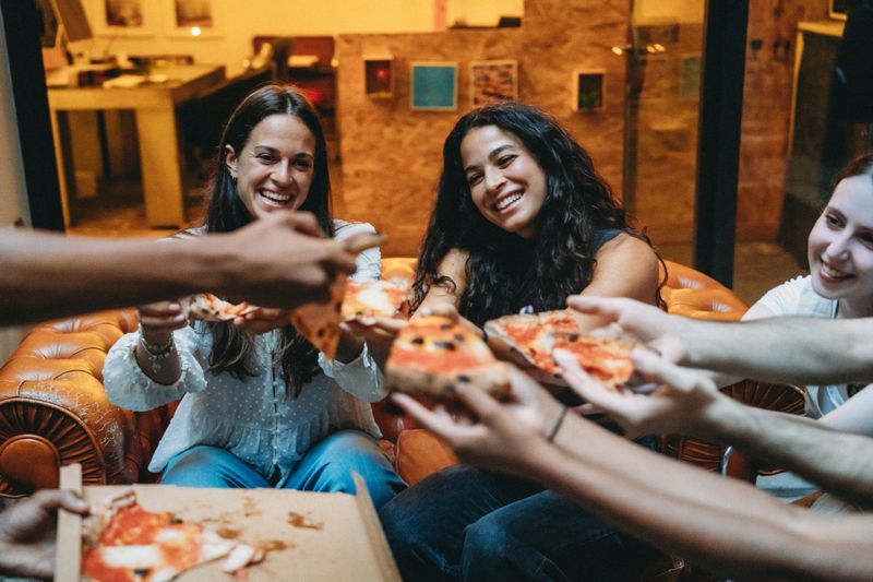 Cheerful business colleagues enjoying pizza together during a relaxing break in the office, fostering camaraderie and teamwork