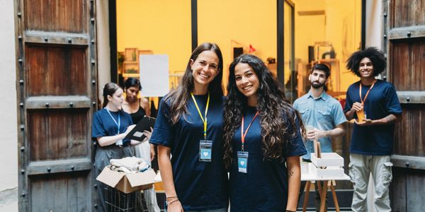 A group of smiling volunteers at an event, two women in front.