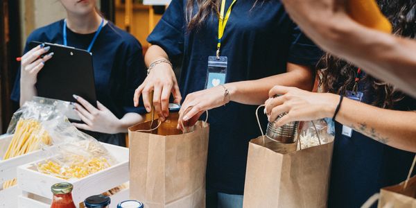 Volunteers packing food supplies into paper bags for distribution.