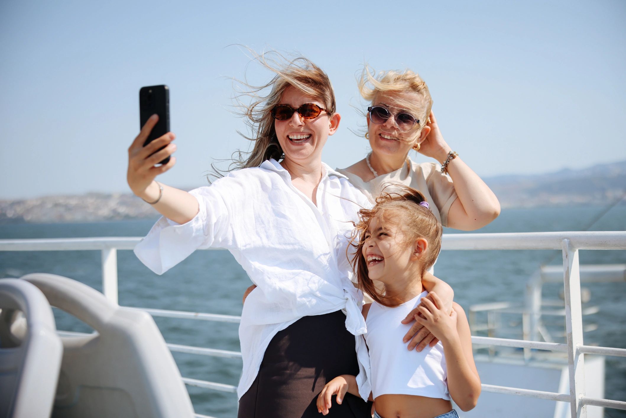 A happy family smiling and taking a selfie on the open deck of an international  ocean cruise ship.