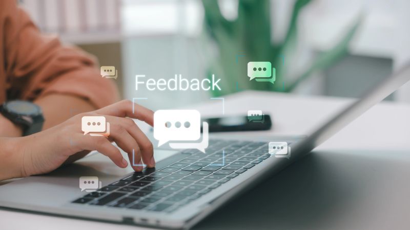 User typing feedback on laptop with digital chat icons, representing online review system, user experience improvement, customer support, and communication technology.