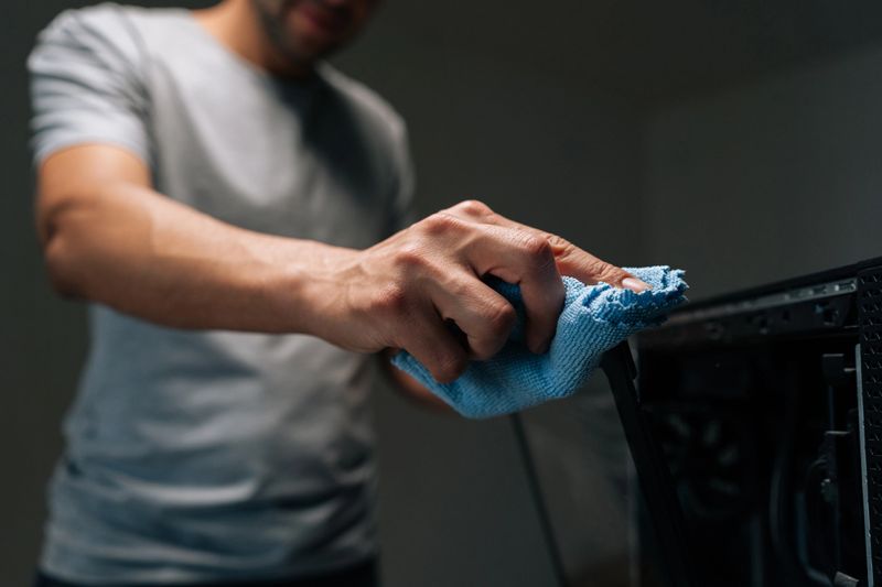 Technician carefully cleaning glass panel of modern computer case with microfiber cloth, ensuring dust and fingerprints removed for optimal appearance and performance. Concept of service, cleaning PC.